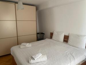 Central Exclusive Apartment/Penthouse في بيتولا: غرفة نوم بسرير ابيض عليها منشفتين