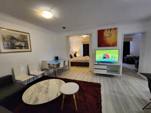 salon z kanapą, stołem i telewizorem w obiekcie PERTH CBD APARTMENTS w mieście Perth