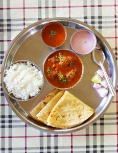 a plate of food with rice and soup and chapatis at Sea Bliss Resort in Kolthare