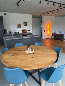 una mesa de madera en una cocina con sillas azules en Neubau Grüner Wolpertinger Designwhg 106qm Barrierefrei en Breitbrunn am Chiemsee
