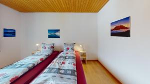 duas camas num quarto branco com pinturas na parede em Feriensiedlung True 7 em Scuol