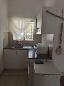 eine kleine Küche mit einem Waschbecken und einem Fenster in der Unterkunft Whimsical in Groutfontein