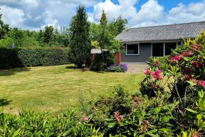 een tuin met een huis en wat bloemen bij Thuya Rica house (1.6km to Legoland) in Billund