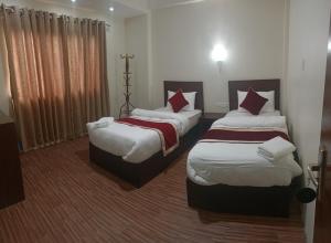 a hotel room with two beds with white and red pillows at Hotel Down To Earth in Kathmandu
