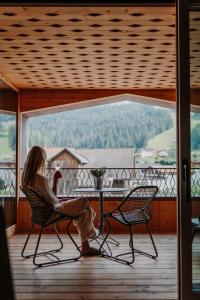 a woman sitting in a chair on a porch at ATTO Apartments in San Candido