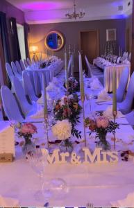 une grande table avec des tables et des chaises blanches ainsi que des fleurs dans l'établissement Strandhotel Vier Jahreszeiten Buckow, à Buckow