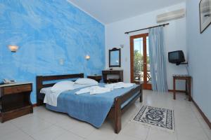 a bedroom with a bed and a blue wall at Eri Hotel in Parikia