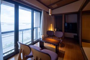 d'une chambre avec des chaises, une table et de grandes fenêtres. dans l'établissement Taiseikan, à Atami