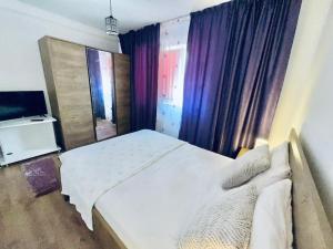 a bedroom with a white bed and a television at Apartament in Regim Hotelier in Bacău