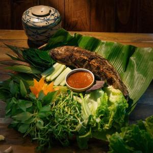 a plate of food on a banana leaf with a dipping sauce at Troh Bư's Bungalows in Buôn Niêng