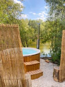 einen Whirlpool mit einem Stuhl neben einem Teich in der Unterkunft Le repaire des impressionnistes in Amenucourt