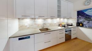 a kitchen with white cabinets and a sink at Chasa Vista Pisoc in Scuol