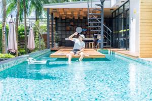 un hombre sentado en el borde de una piscina en Book a Bed Poshtel - SHA Plus en Phuket