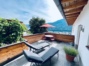 balkon z krzesłami, stołem i parasolem w obiekcie Das Stubai - exklusiv, einzigartig & nachhaltig w mieście Fulpmes