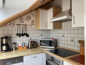 a kitchen with white cabinets and a microwave at Ferienwohnung Rosengarten in Osburg