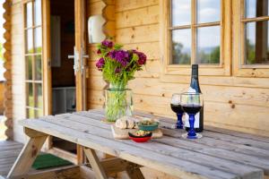 a wooden table with a vase of flowers and a glass of wine at Moor View Cabin (Oak Tree Lane) in Okehampton +12 photos