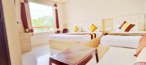ein Hotelzimmer mit zwei Betten und einem Fenster in der Unterkunft Sanjog Resort in Kota