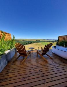 two chairs and a table on a wooden deck at Parador dos Canyons in Cambara do Sul