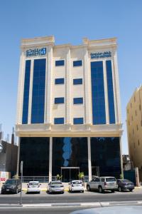 duży budynek z samochodami zaparkowanymi przed nim w obiekcie بنزرت للشقق الفندقيه w mieście Al-Hufuf