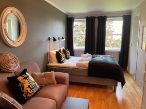 a bedroom with a bed and a couch and a mirror at Brattrein Hotell - Unike Hoteller in Notodden