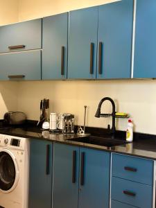 a kitchen with blue cabinets and a sink and a washing machine at شاليهات كابري وماديرا درة العروس in Durat Alarous