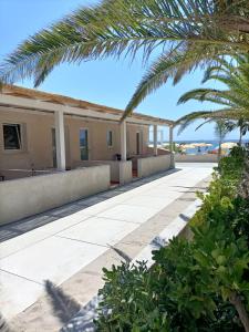 a walkway with palm trees in front of a building at Lido Di Alghero Rooms on the Beach in Alghero