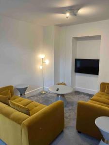a living room with a couch and a table and a tv at The Mews, private parking included, Windermere in Windermere