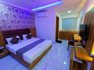 een slaapkamer met een bed, een tv en een bureau bij HOTEL ROCK in Anand