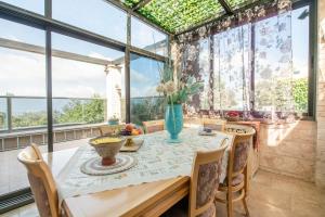 a dining room with a table and chairs and large windows at הים פוגש את ההר- בית בלב הגליל Sea & Mount in Adamit