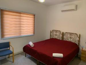 1 dormitorio con 1 cama roja y 2 toallas en Beit Philodemus, en Um Qeis