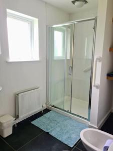 a bathroom with a glass shower and a sink at Nara Seaside Retreat in Cultra