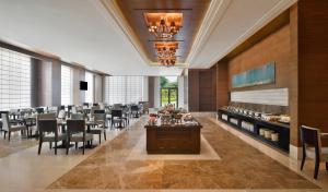 Sheraton Grand Palace Indore في إندوري: غرفة طعام كبيرة مع طاولات وكراسي