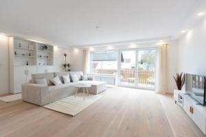 a white living room with a couch and a television at Stylish Apartment near Munich in Moorenweis