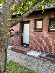 una casa de ladrillo con una puerta y un árbol en Schaumis Hus, en Tinnum