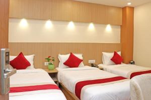 Hotel Nilakantha Pvt. Ltd في كاتماندو: ثلاثة أسرة في غرفة الفندق مع وسائد حمراء