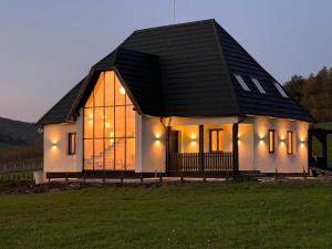 a small house with a black roof on a field at arra housing near Bistrita in Şintereag