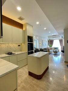 a large kitchen with white cabinets and a living room at Insta-worthy staycation at 2BR luxury Apt - Podomoro Empire Tower in Medan