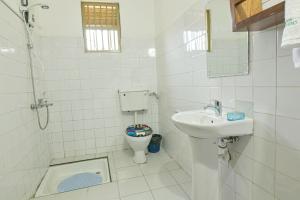 a white bathroom with a toilet and a sink at Cycad Entebbe Guest House in Entebbe