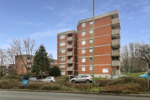 un grand bâtiment en briques avec des voitures garées dans un parking dans l'établissement Unterkunft in Bergkamen, à Bergkamen