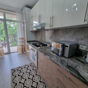 a kitchen with white cabinets and a counter with a microwave at ApartHotel city centrum in Chişinău