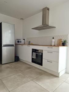 cocina con armarios blancos y nevera en Appart moderne avec jardin à 5min de la plage, en Sainte-Marie-la-Mer