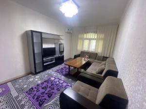 a living room with a couch and a table and a television at Euroasia in Samarkand