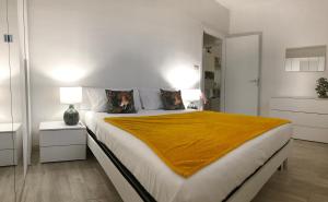 1 dormitorio blanco con 1 cama grande con manta amarilla en FamilyBO Apartments Bologna Delight - front station, en Bolonia
