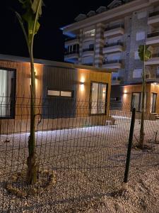 a fence with a tree in front of a building at Tiny House Sitesi in Alanya