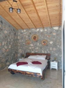 een slaapkamer met een bed en een stenen muur bij Fethiye Havuzlu Villa in Fethiye