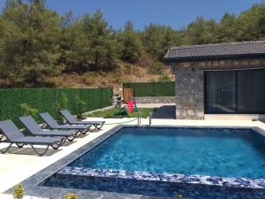 een zwembad met ligstoelen naast een huis bij Fethiye Havuzlu Villa in Fethiye