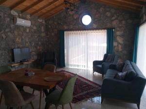 een woonkamer met een tafel en stoelen en een televisie bij Fethiye Havuzlu Villa in Fethiye