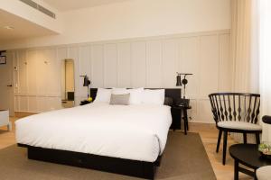 a bedroom with a large white bed and a chair at Coppersmith Hotel in Melbourne