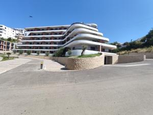 un grand bâtiment blanc en face d'un parking dans l'établissement Allure Apartments, à Ulcinj