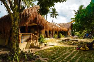 a house with a thatched roof and a yard at Ozen Freediving Hostel in General Luna